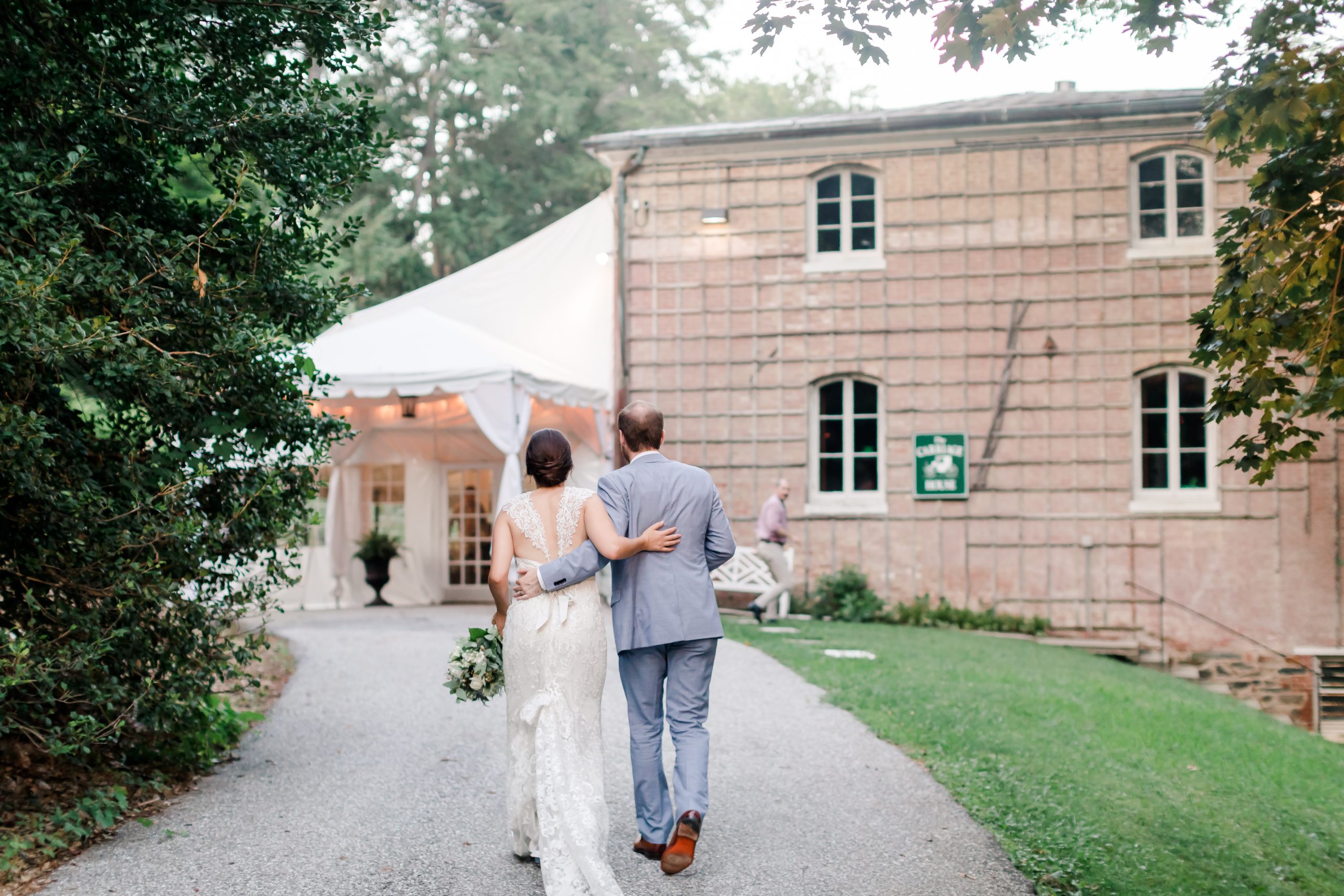 bride and groom walking toward carriage house